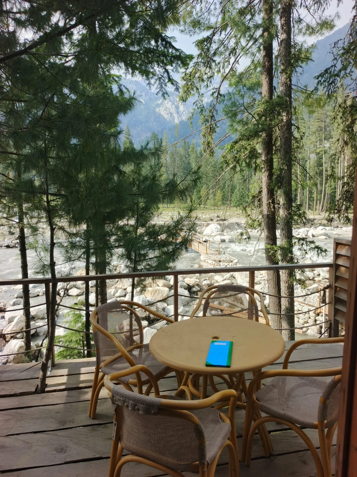 A table and wicker chairs on the terrace beside the river